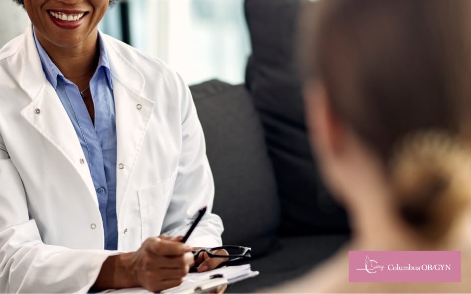 Out-of-focus woman in the foreground with a focused view of a doctor listening attentively